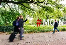 Fußgänger:innen vor dem MOIN-Schriftzug in den Wallanlagen