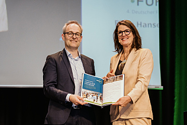 Staatsrat Enno Nottelmann übergibt die unterzeichnete Urkunde der Charta für das Gehen an Bronwen Thornton von Walk21 