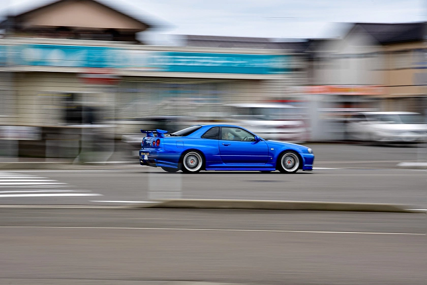 Rasendes blaues Auto auf Straße als Symbolbild für Thema Auotposing