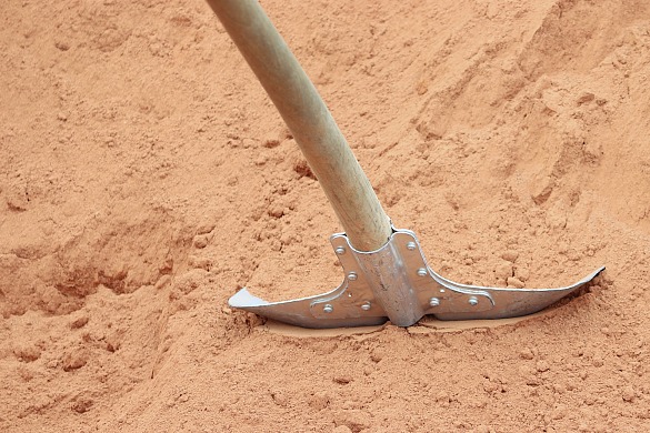 Spaten steckt in einem Sandhaufen