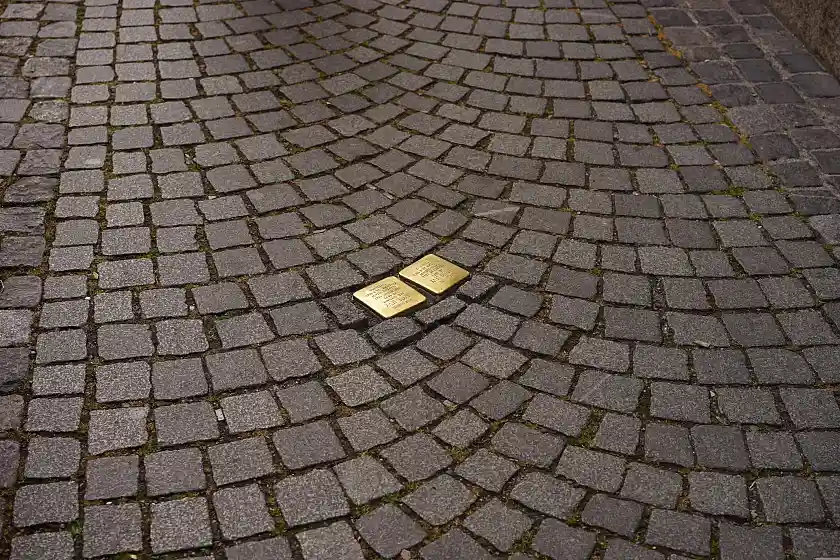 Zwei goldene Stolpersteine inmitten einer Pflasterung
