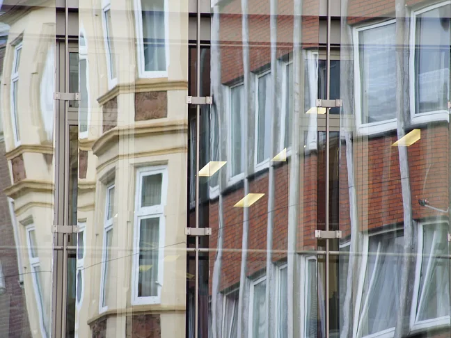 Glasfassade, in der sich Häuser spiegeln