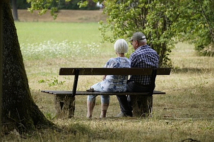 Das Bild zeigt zwei Rentner auf einer Bank im Park